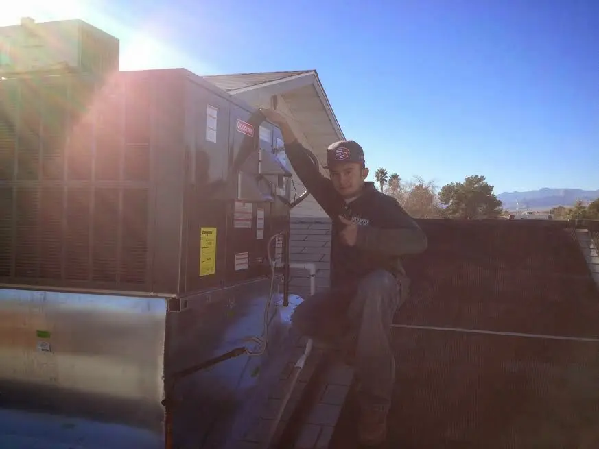 HVAC technician performing AC Tune-Up on a rooftop unit in Lansing